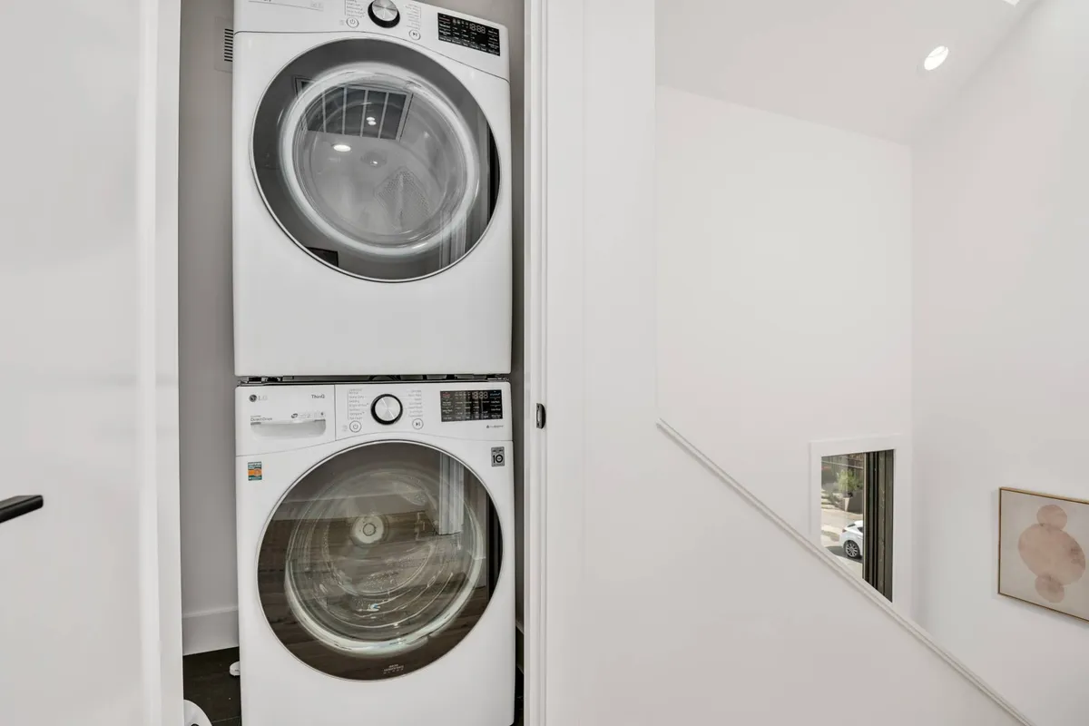 A bright, efficient laundry area featuring modern washer and dryer units, minimalist decor, and light-colored walls. The space is organized and practical, emphasizing convenience.