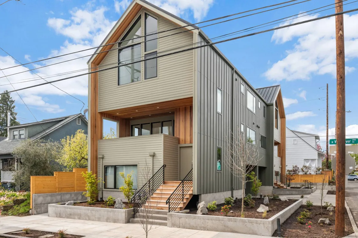 This exterior image showcases the modern architecture of Williams Retreat Unit 1, with clean wood accents, a landscaped garden, and a welcoming staircase entrance. The scene feels open and approachable, suggesting easy access and a pleasant neighborhood environment.