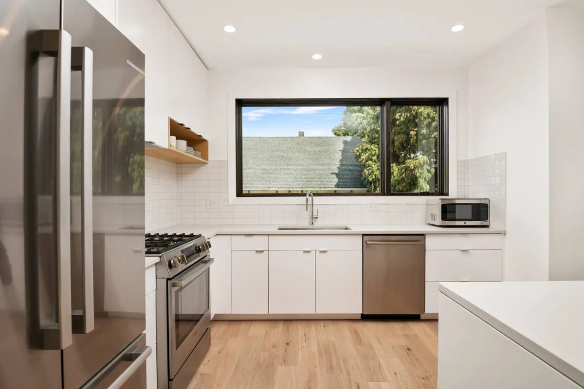 A modern bathroom with sleek stainless steel appliances, a large window that floods the space with natural light, and minimalist cabinetry. The clean lines and neutral tones evoke a spa-like feel, making the bathroom both functional and restorative.