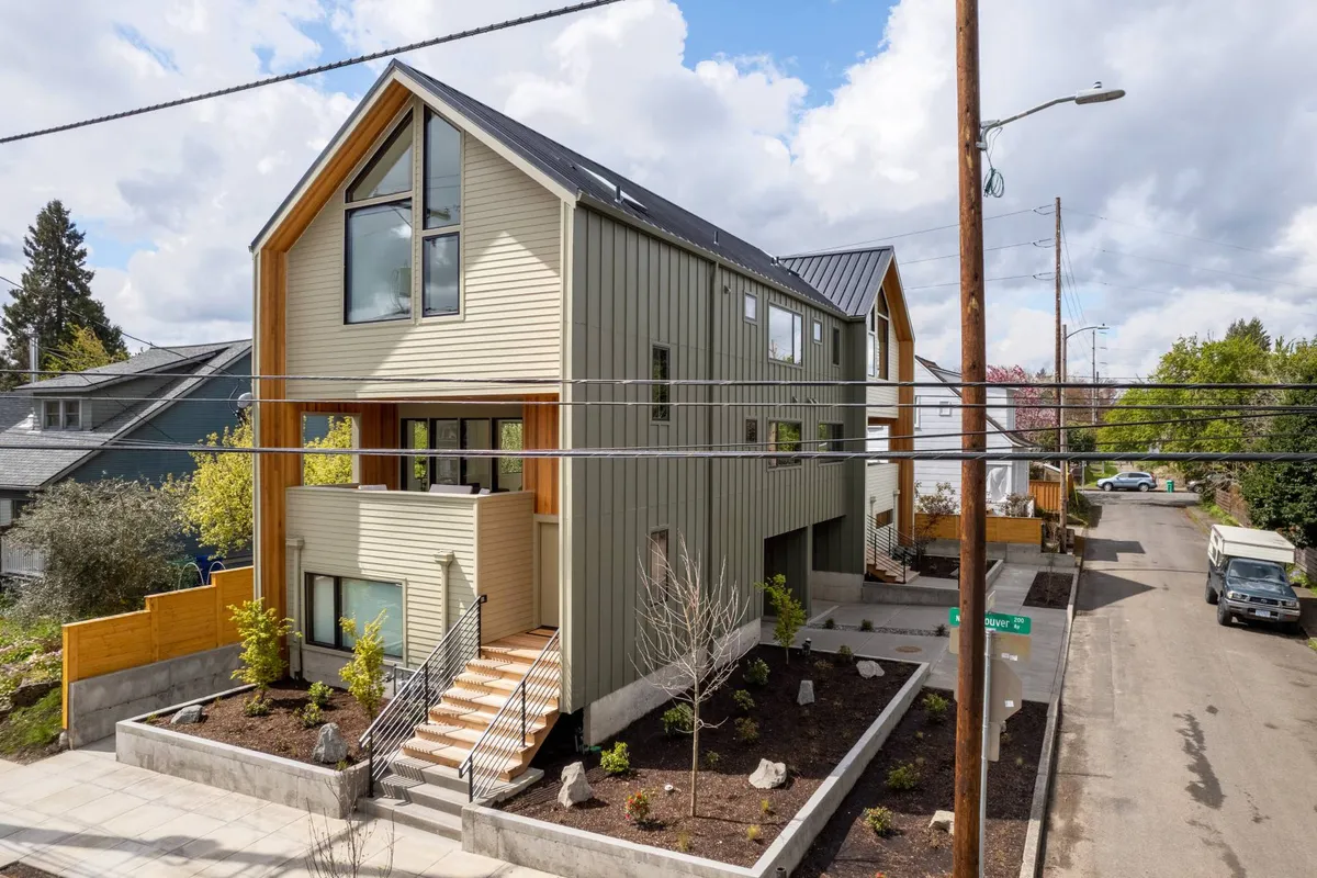 An inviting exterior shot of a modern house with wood accents, a staircase entrance, and a landscaped garden. The welcoming porch and greenery evoke a sense of community and are ideal for families returning from city adventures or relaxing outdoors.